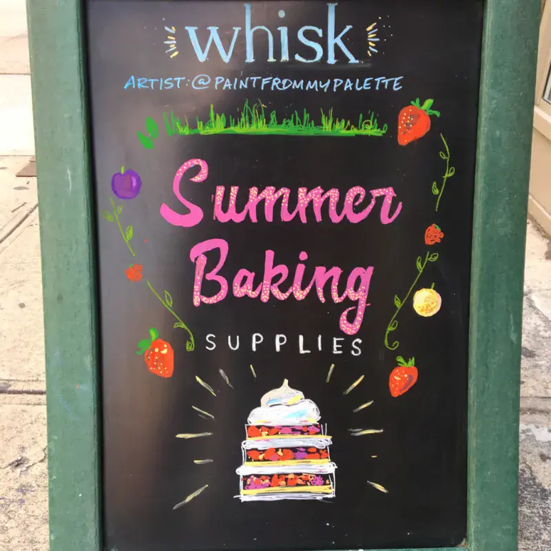 Hand-lettered chalkboard sign painted live for a storefront